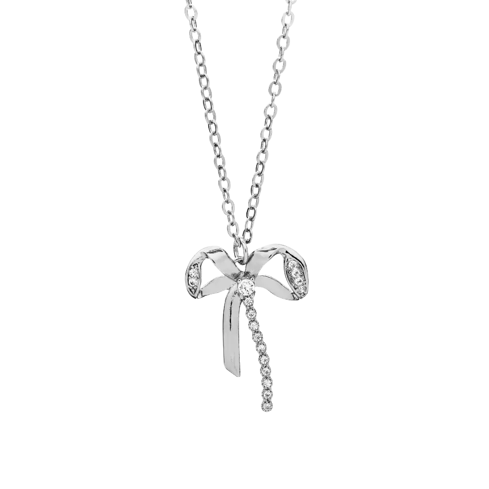 JN059_main "A premium white gold tone necklace from the brand Arria by Kiss. The necklace is elegantly designed with a bow motif, adorned with cubic zirconia for added sparkle. It is displayed on a black card that highlights its price of $12.99 and notes 